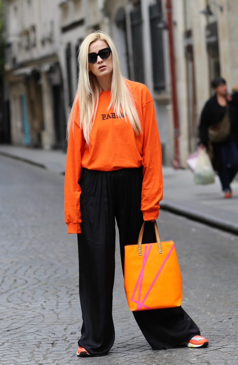 Sweatshirt Orange, schwarze Hose, Sonnenbrille, Shopper