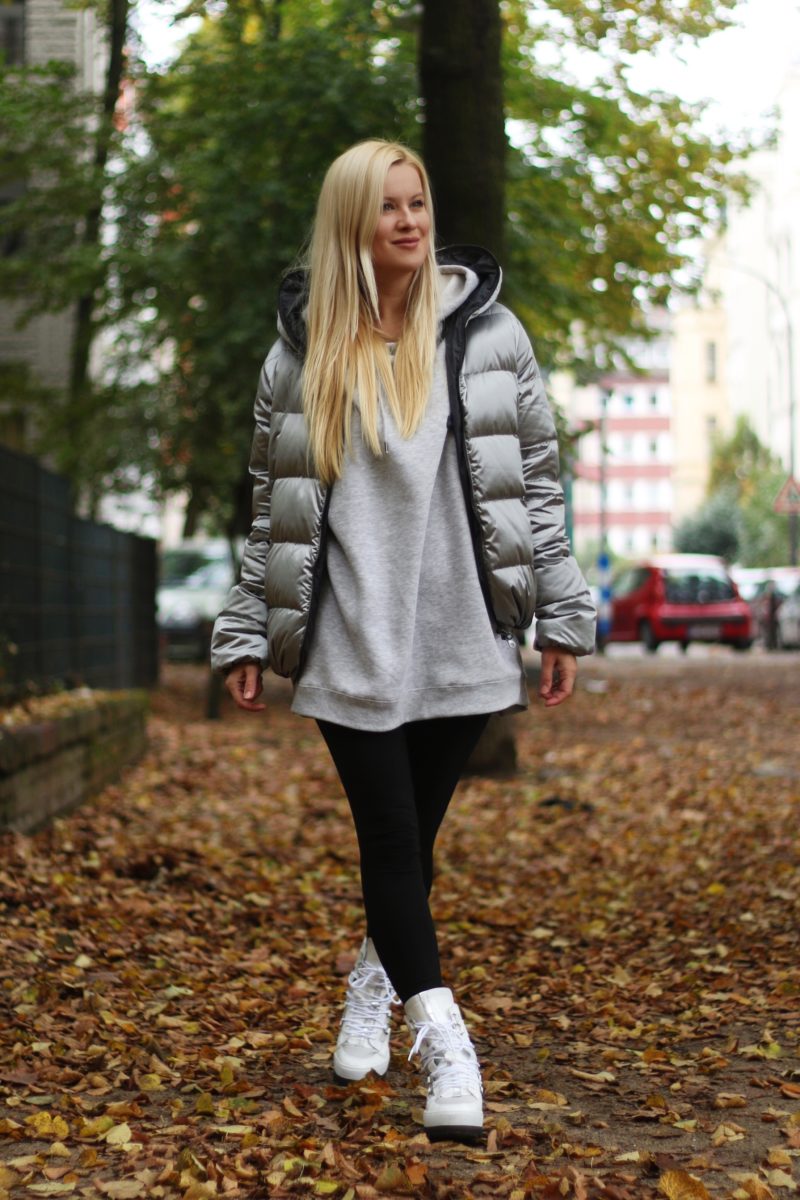 Silberne Winterjacke, grauer Hoodie, weiße Schuhe