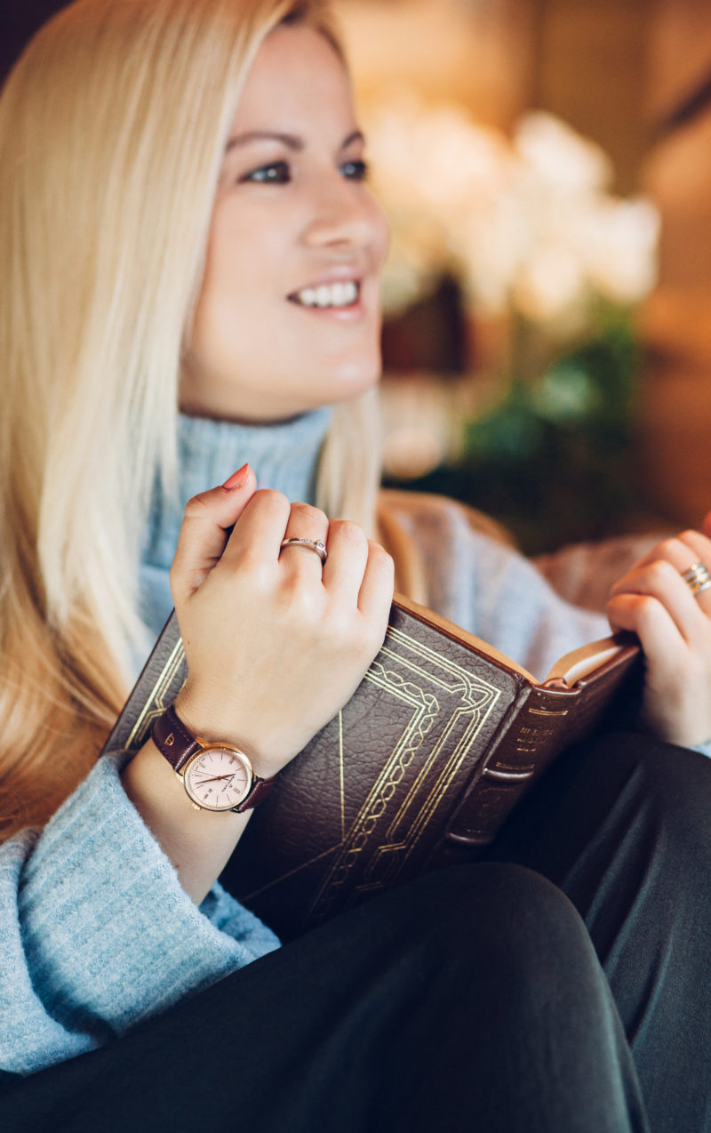 blond, buch, blauer rollkragenpullover, schmuck