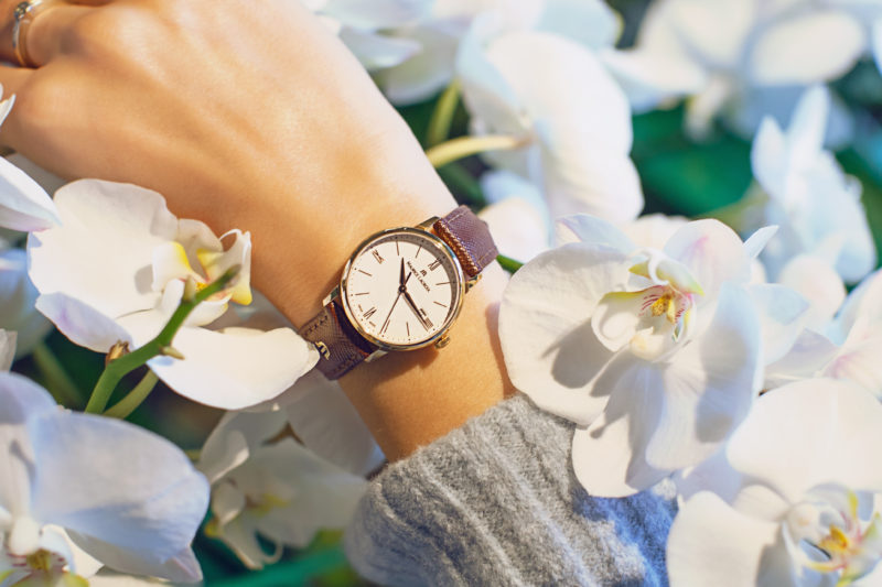 gold uhr, braunes leder armnad, weißes ziffernblatt, weiße blumen