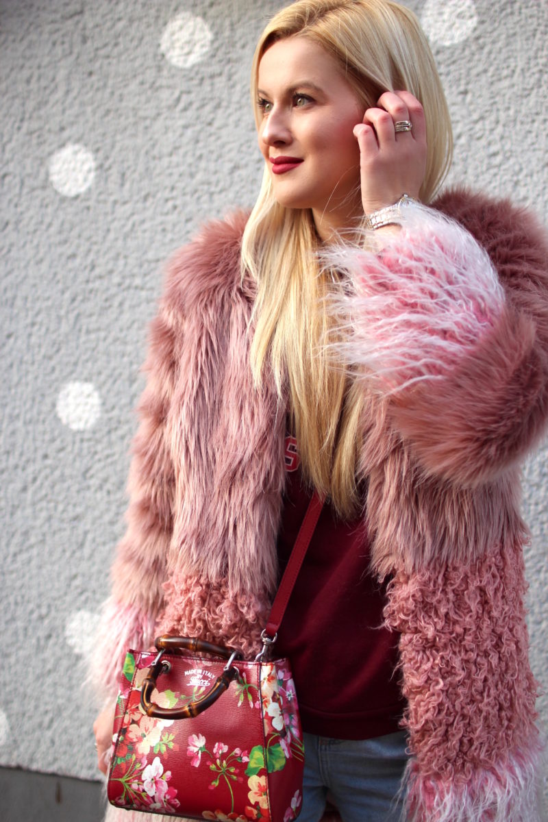 pink red fake fur coat, gucci bag, grey wall