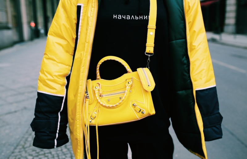 yellow mini balenciaga cross over bag, black sweater, oversized coat